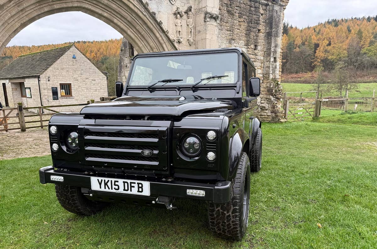 A black Defender 90 beneath a stone abbey arch
