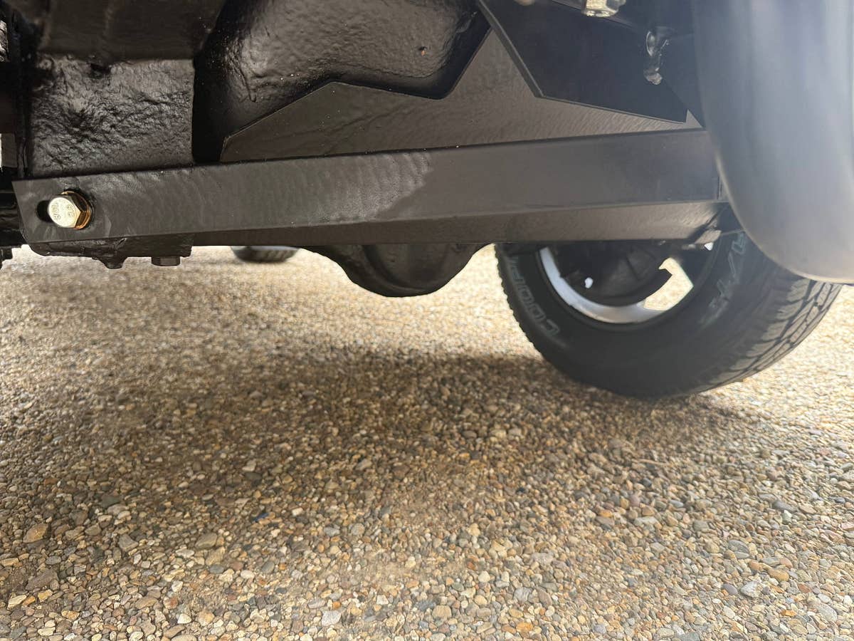 Front axle, radius arm and coil spring beneath a prepared Defender