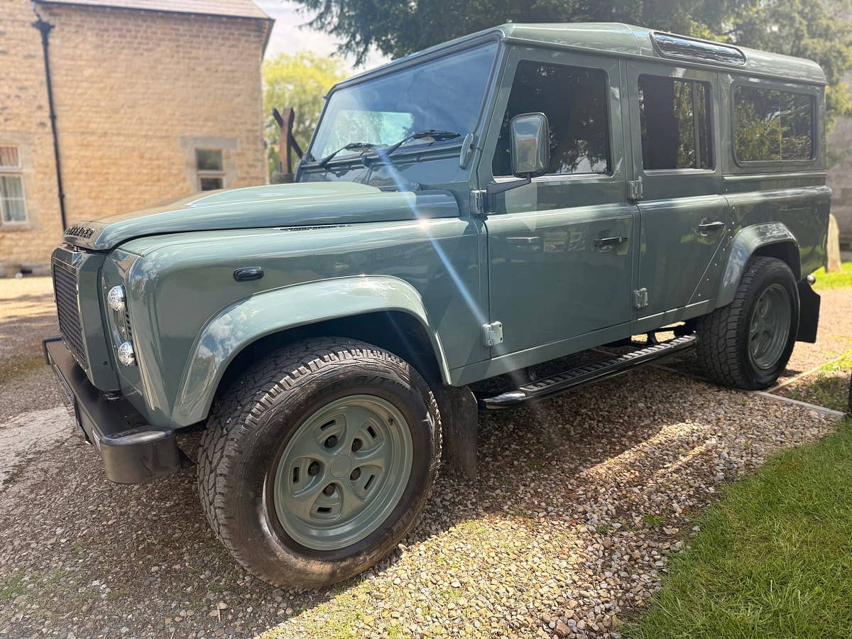 A heritage-green StraightRange Defender 110 on a village lane