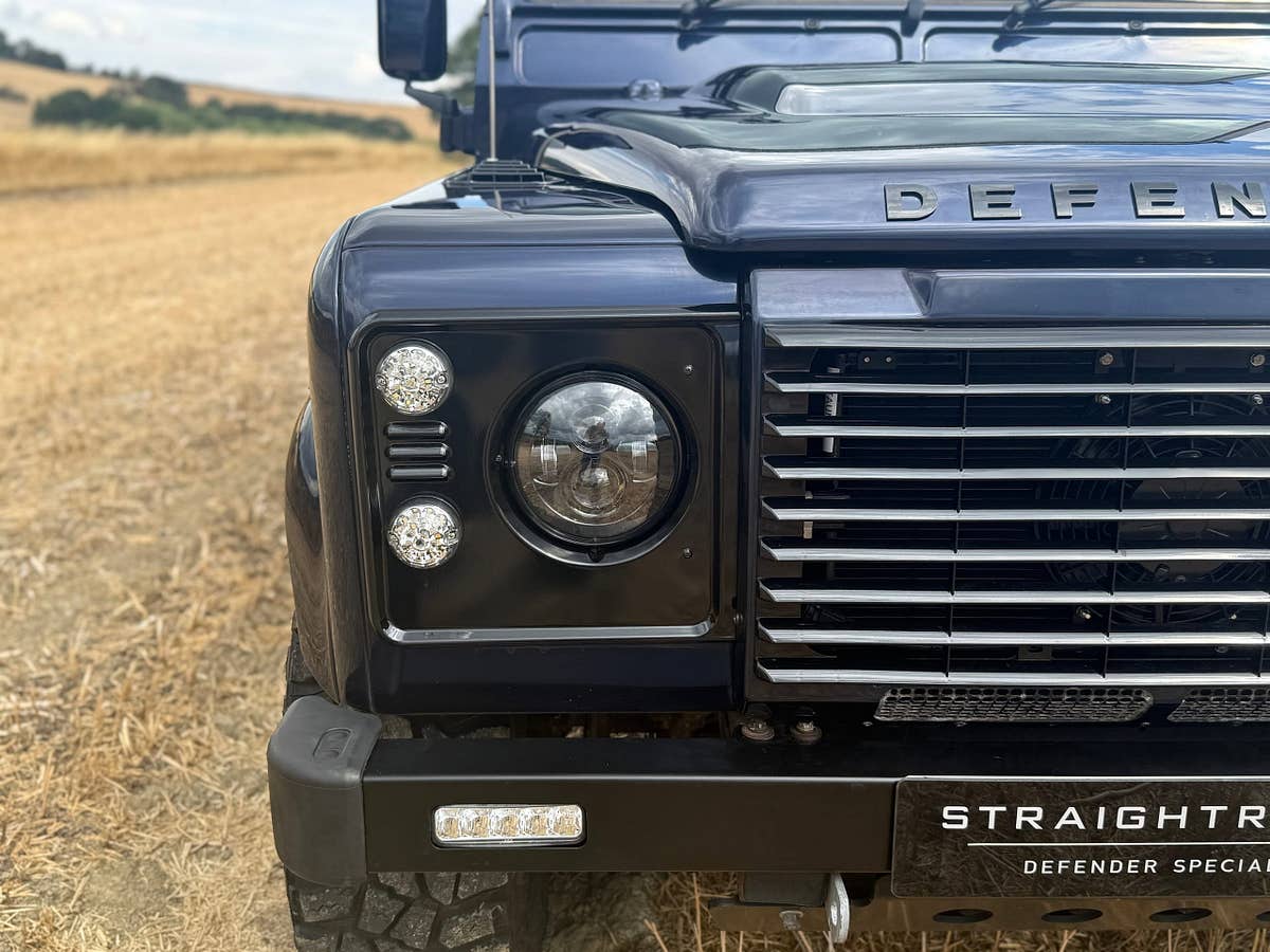 A black Defender 90 photographed beneath a stone abbey arch