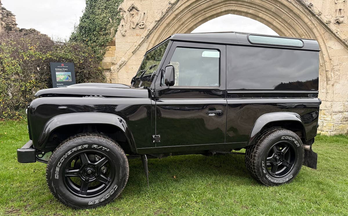 A black Defender 90 alongside a stone abbey wall
