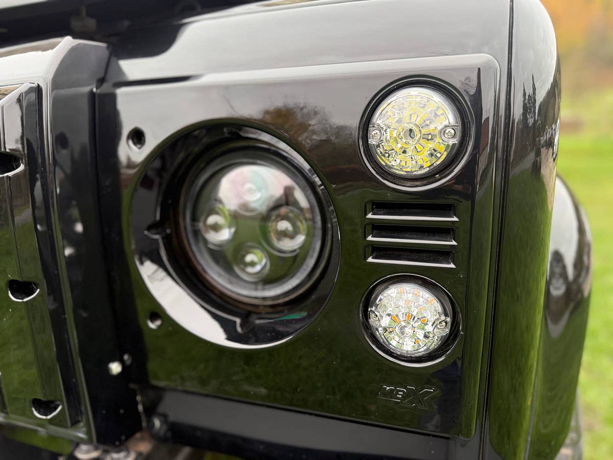 Gloss black wing and headlamp detail on a finished Defender