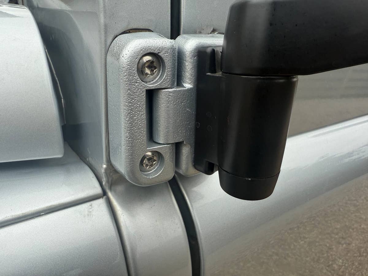 A door hinge and check strap on a prepared Defender