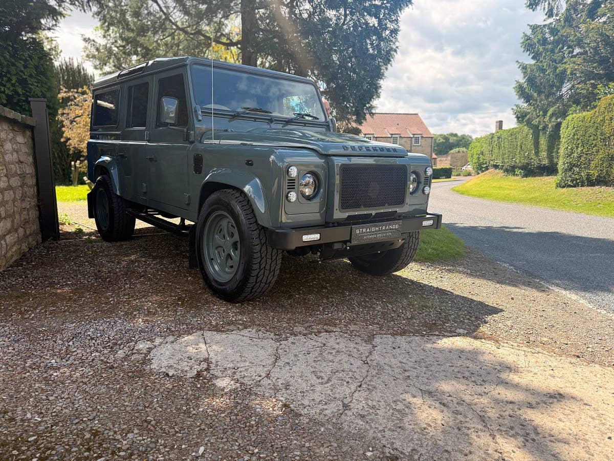 A heritage-green StraightRange Defender 110 on a village lane