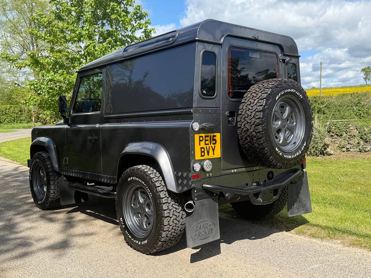 A grey Defender 90 on a country lane