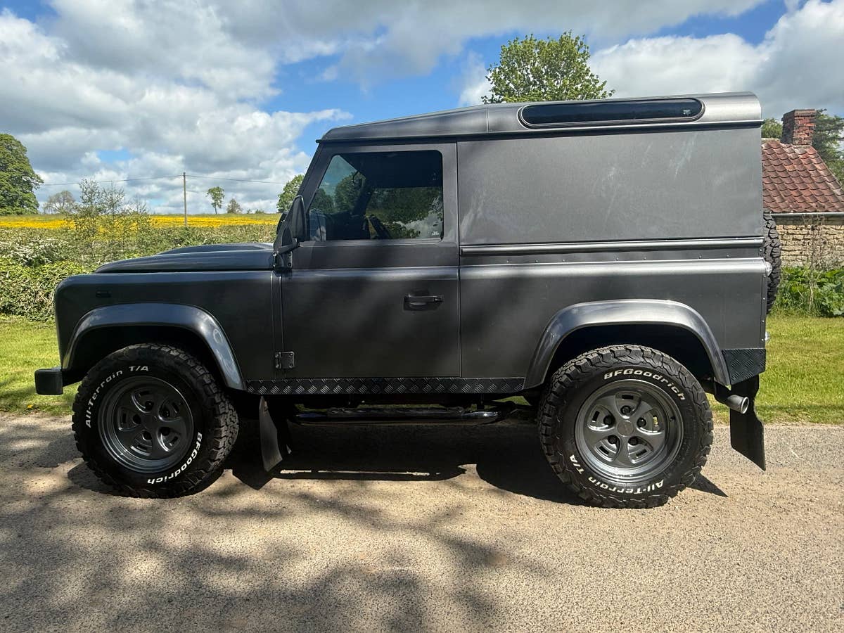 A grey Defender 90 on a country lane