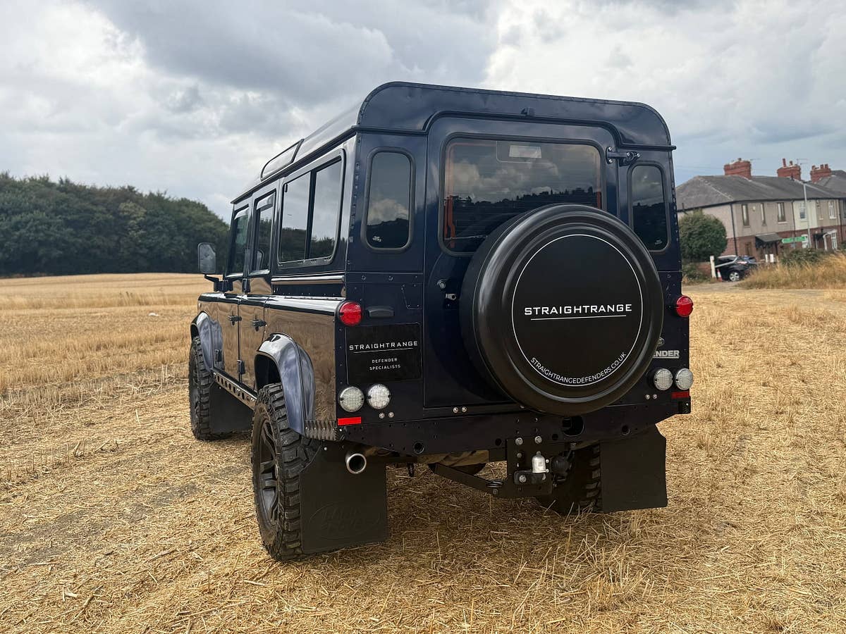 A navy StraightRange Defender 110 in a stubble field