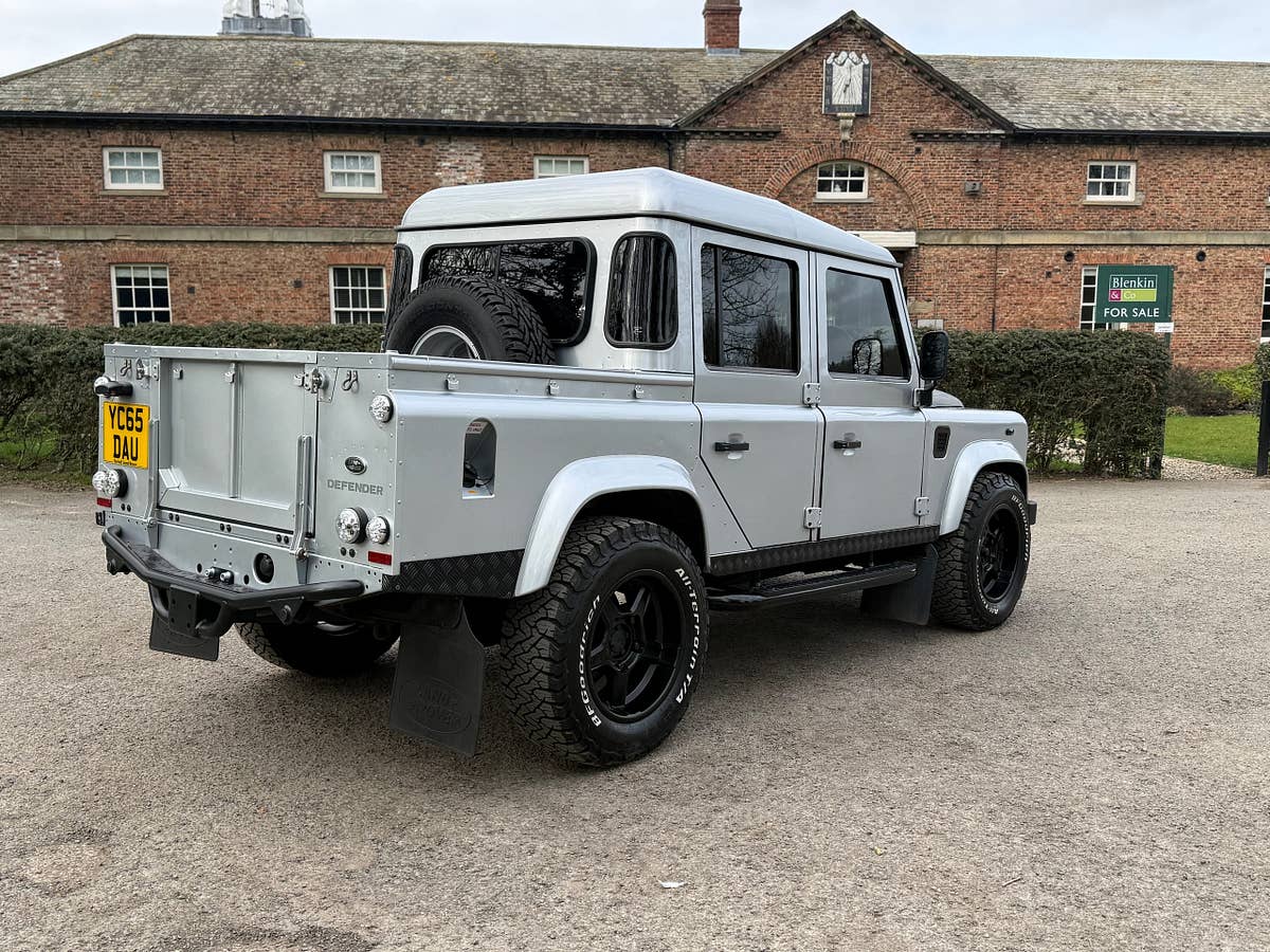 A silver Defender 110 double-cab pickup, rear three-quarter view